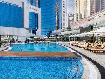 Hotelový bazén s lehátky a slunečníky v městském prostředí