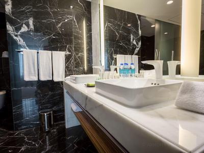 Modernes Badezimmer mit schwarzer Marmorwand, weißem Waschbecken und Handtüchern.