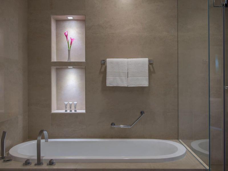 Modernes Badezimmer mit eingebautem Regal, Badewanne und Glastrennwand.