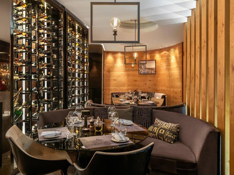 Gemütliches Restaurant mit runden Tischen, Holzwänden und einem großen Weinregal.