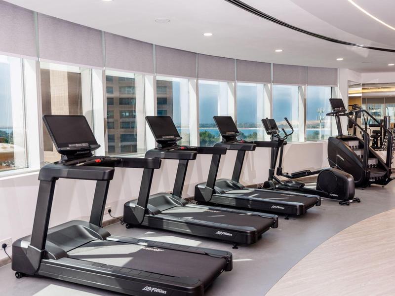 Moderner Fitnessraum mit mehreren Laufbändern und großem Panoramafenster.