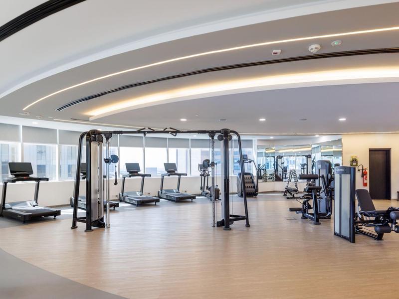 Moderner Fitnessraum mit Laufbändern, Kraftgeräten und integriertem Beleuchtungssystem an der Decke.