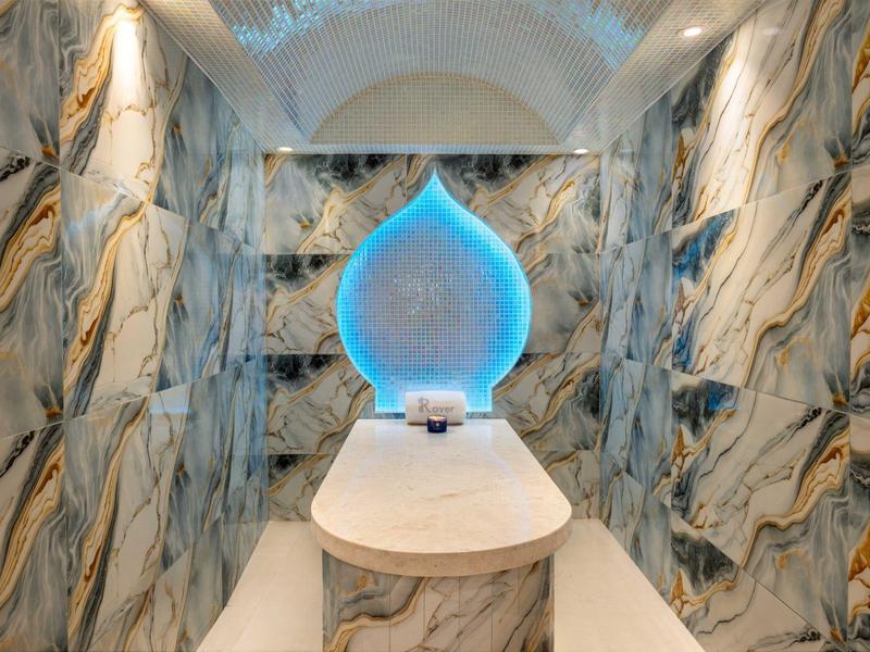 Luxuriöser Raum mit golden gemusterten Marmorwänden und blau leuchtendem Wasserfall-Dekor.