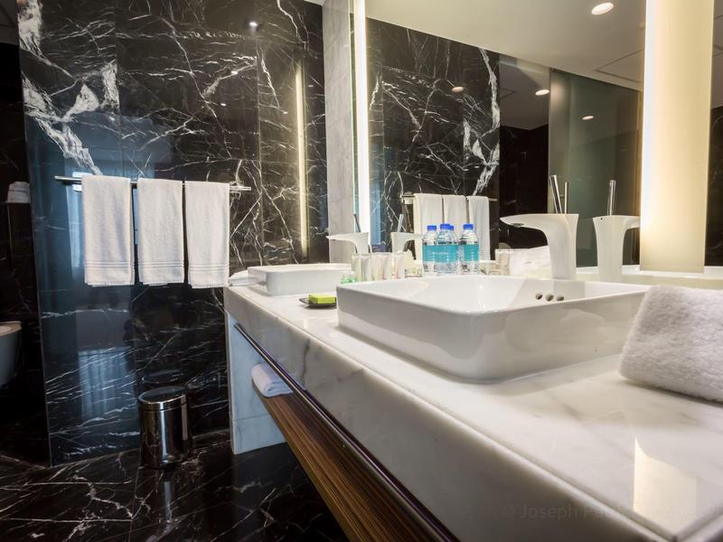 Modernes Badezimmer mit schwarzer Marmorwand, weißem Waschbecken und Handtüchern.