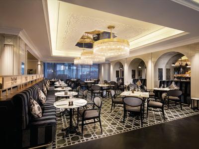 Nowoczesny pokój hotelowy z podwójnymi łóżkami i panoramicznym widokiem na morze przez duże okna.