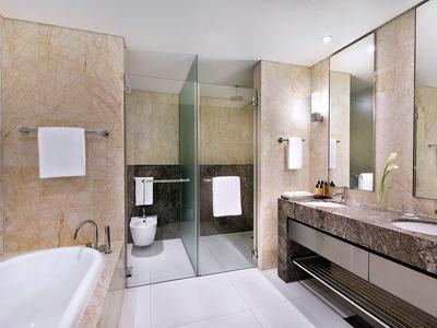 Modernes Hotelbad mit großer Badewanne, Glasdusche und Doppelwaschbecken mit Marmorplatte.