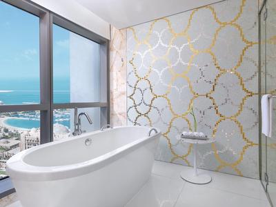 Luxuriöses Badezimmer mit freistehender Badewanne, großer Fensterfront und Meerblick.