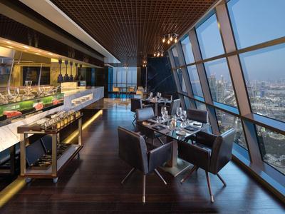 Restaurante moderno con grandes ventanas y vista a la ciudad en un hotel.