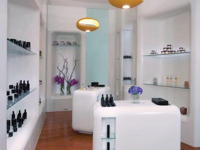 Estudio de uñas blanco y moderno con suelo de madera y lámparas amarillas para huéspedes del hotel.