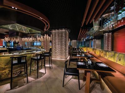 Restaurante de hotel moderno con área de bar elegante, iluminación tenue y asientos de estilo.