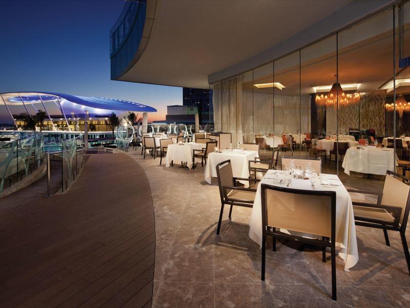 Restaurante moderno del hotel con vista a la piscina y luz ambiental nocturna.