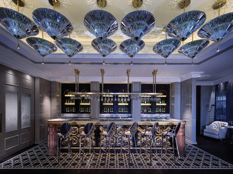 Terraza de restaurante con mesas y sillas, vista al mar y edificios modernos al fondo.