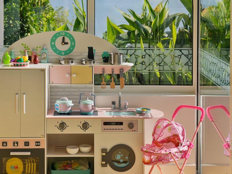 Acogedora esquina de cocina con electrodomésticos retro y sillas rosas junto a grandes ventanas con vista al jardín.