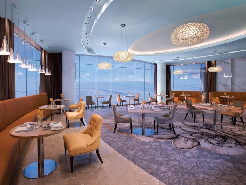 Restaurante de hotel elegante y moderno con ventanas panorámicas y asientos cómodos.