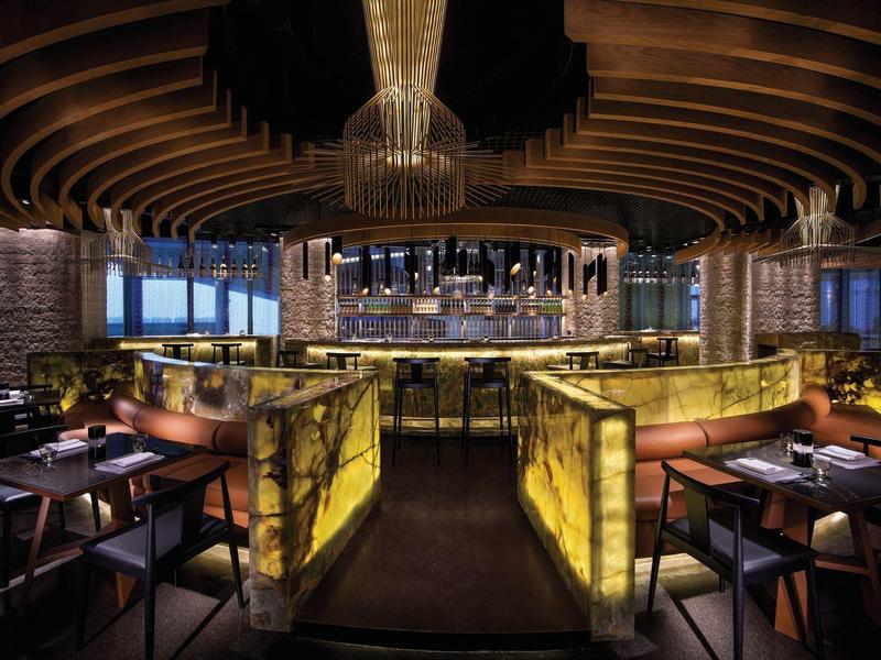 Restaurante de hotel elegante con mesas iluminadas cálidamente y diseño moderno del techo.