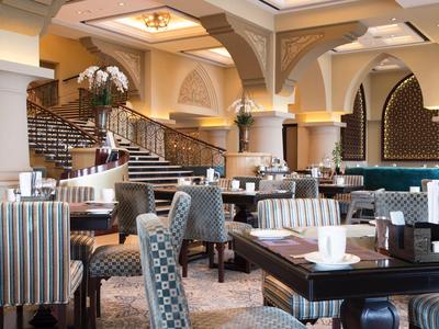 Elegantní hotelová restaurace s různorodým posezením, pruhovanými a čalouněnými židlemi a decentním osvětlením.