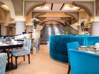 Elegantní hotelový lounge s modrými křesly a schodištěm v pozadí