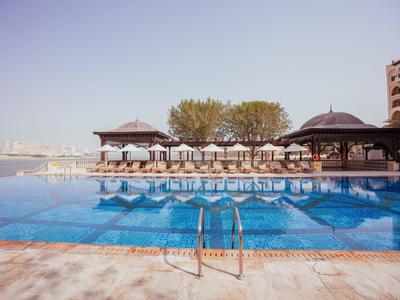 Gran piscina con vistas al río, rodeada de pabellones y árboles en un día tranquilo.