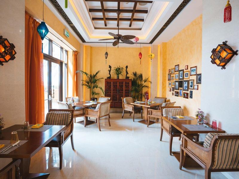 Habitación de hotel luminosa y acogedora con sillas, mesas y paredes amarillas cálidas.