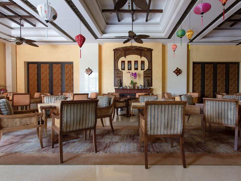 Área de lounge elegante de hotel con sillas de madera antiguas y faroles coloridos en el techo.