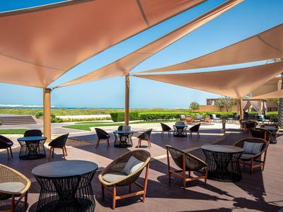 Offene Terrasse mit moderner Sitzmöblierung und Sonnensegeln mit Blick auf das Meer.