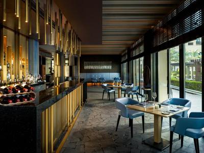 Eleganter Hotelbarbereich mit Sitzgelegenheiten und Blick auf einen Außenbereich durch große Fenster.