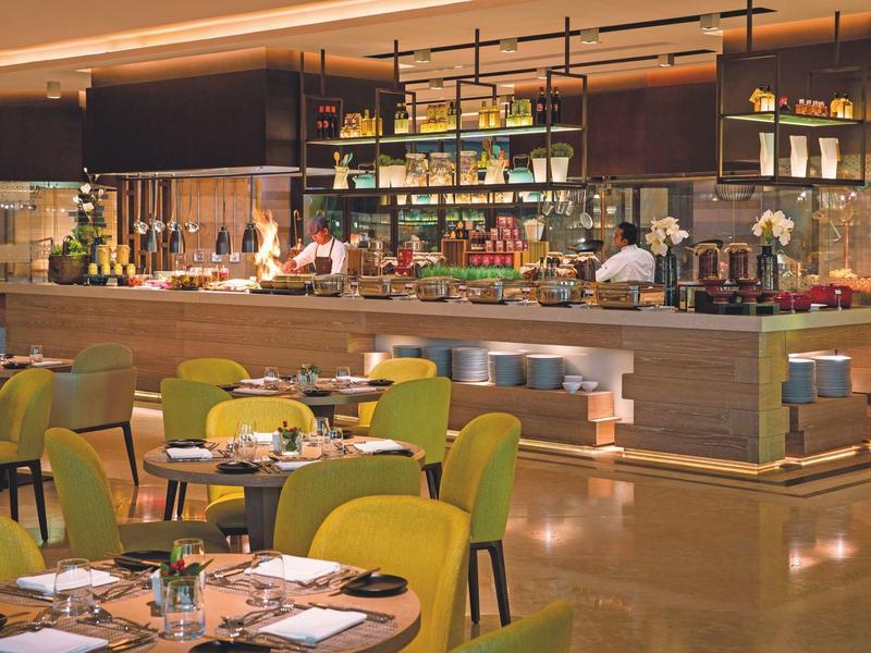 Modern restaurant with green-yellow chairs and a lavish buffet area.