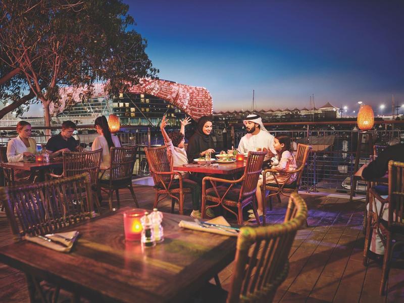 Evening terrace with guests at tables, lit, relaxed outdoor atmosphere