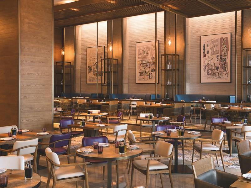 Elegant restaurant with wooden chairs, round tables, and modern wall art in warm lighting.