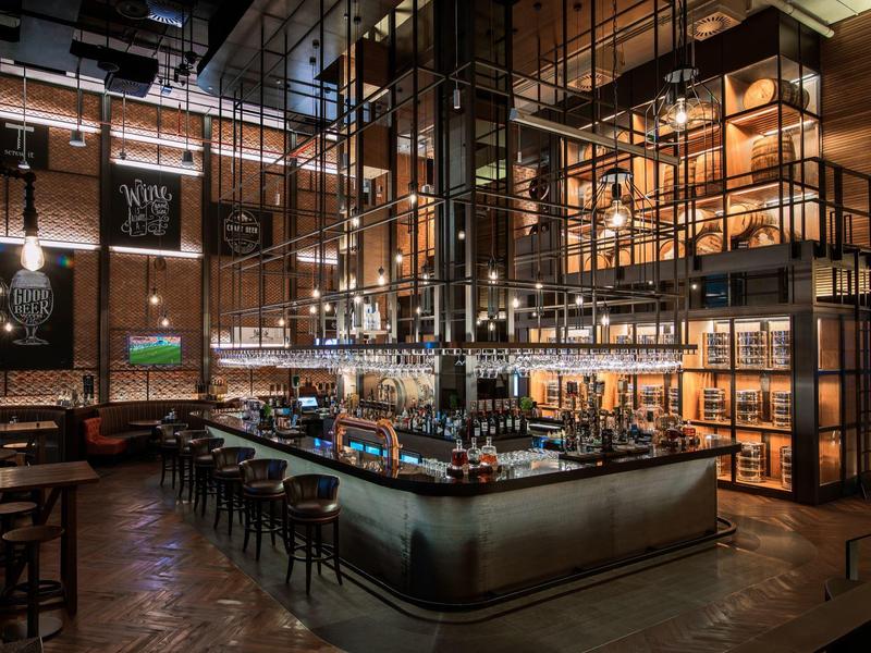 Modern hotel bar area with high ceiling, lighting, and cozy seating.