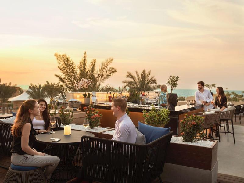 Outdoor restaurant with guests at sunset overlooking the sea