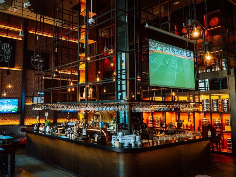 Cozy bar with large TV, modern details, and warm ambiance in a hotel setting.