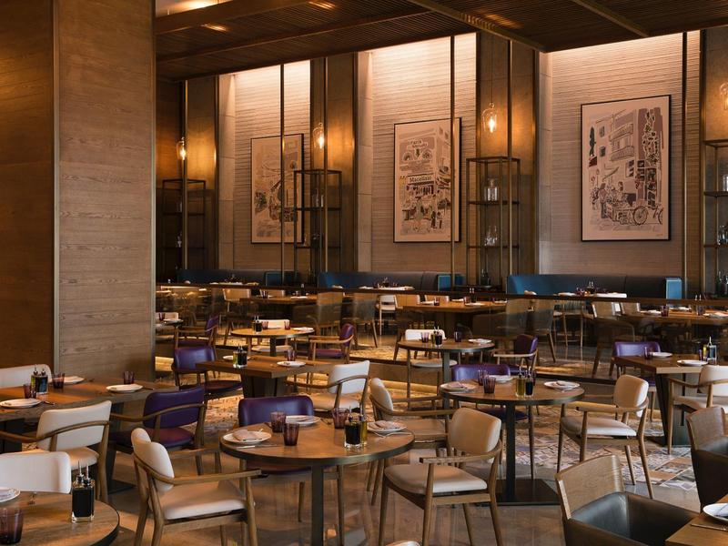 Elegant hotel restaurant with wood-paneled walls, set tables, and warm lighting.