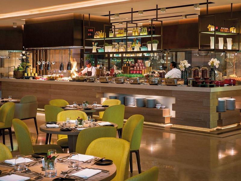 Modern restaurant with green chairs and long bar in elegant ambiance.