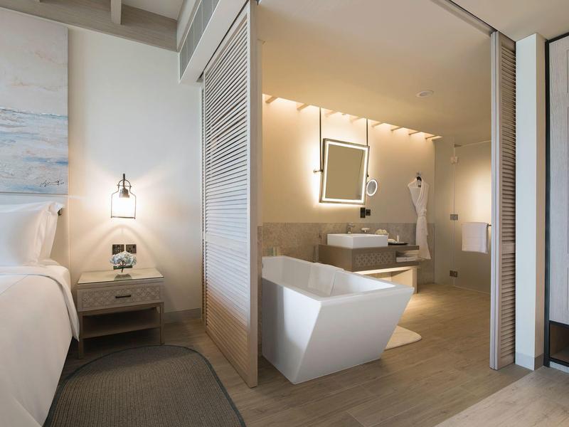 Modern hotel room with integrated bathroom and freestanding bathtub.