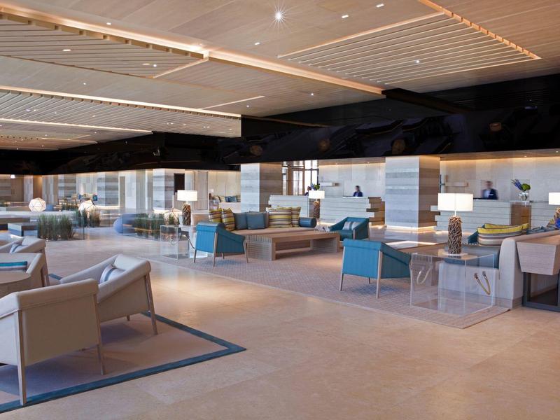 Spacious modern hotel lounge with comfortable chairs and tables in a bright room.