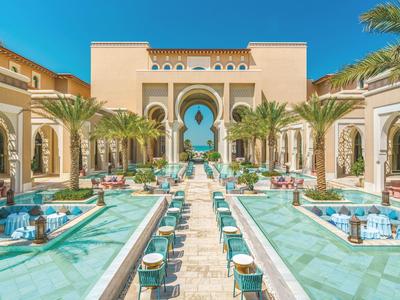 Luxushotel mit Springbrunnen, Palmen und Sitzgelegenheiten entlang eines zentralen Wassergangs.