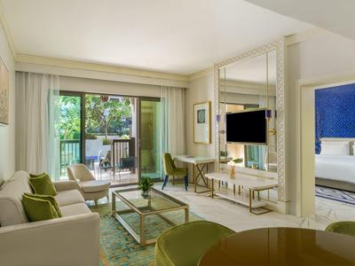 Helles Wohnzimmer mit Sofas, Glas-Couchtisch, TV und Zugang zum Balkon mit Grünblick.