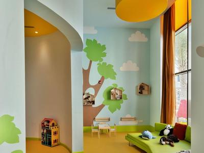 Kinder speelkamer met kleurrijke muren, zachte zitplaatsen en groot raam.