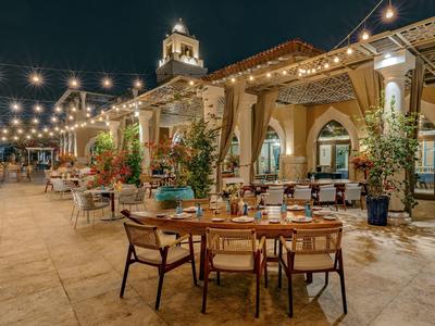 Hotel terrace at night with string lights and arranged tables outdoors.
