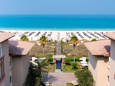 View of a beach with umbrellas from a hotel between two buildings.