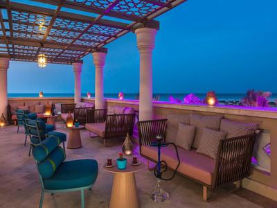 Überdachte Dachterrasse mit Sitzgruppen, Säulen und stimmungsvoller Beleuchtung bei Dämmerung.