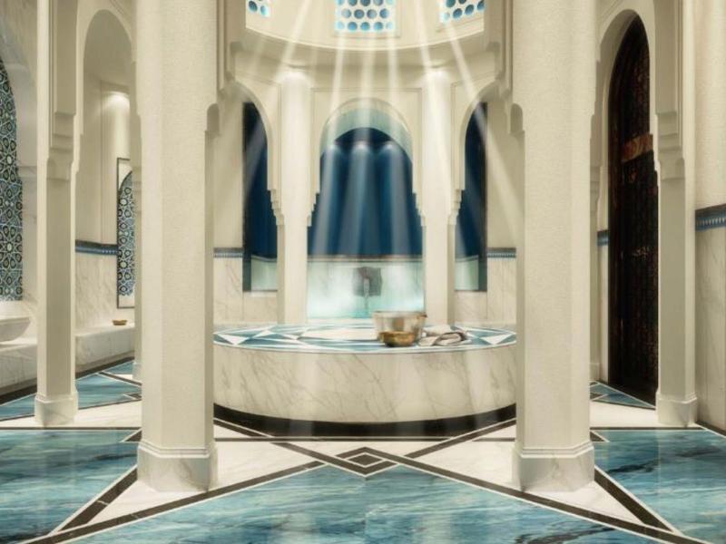 Luxurious hotel spa with elegant columns, blue water, and soft sunlight streaming through.