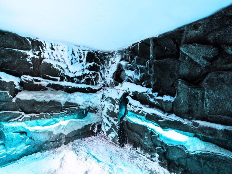 Indoor spa pool with icy stone walls and blue lighting creating a cold atmosphere.
