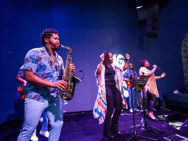 Live band performs energetically on stage at a vibrant hotel event with colorful lighting.