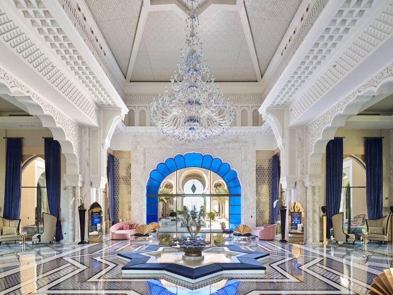 Luxurious hotel lobby with chandelier, elegant furniture, and detailed architectural decorations.