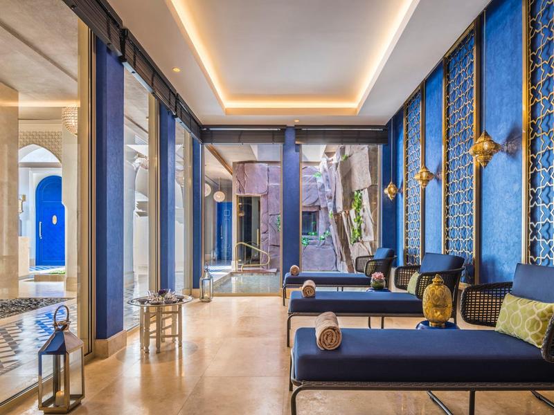Luxurious hotel lobby with blue patterned walls, plush seating, and warm lighting.