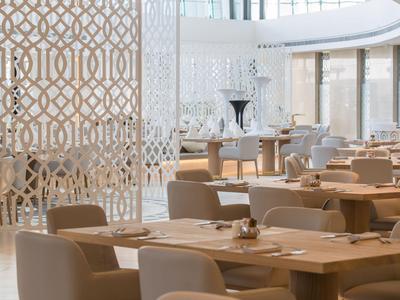 Helles, modernes Restaurant mit beigen Stühlen und dekorativen Trennwänden.