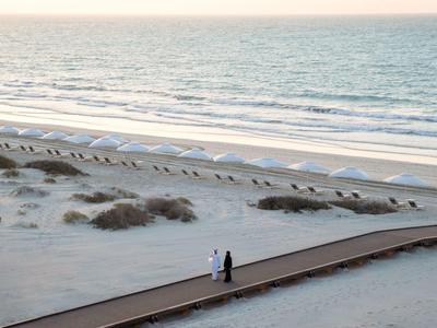 Chambre d'hôtel moderne avec deux lits simples et vue sur la mer à travers de grandes fenêtres.