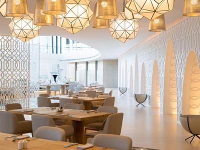 Helles modernes Restaurant mit runden Holzlampen und bequemen Stühlen in warmen Tönen.